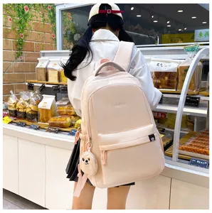 Dettaglio zaino scolaretta nylon rosa, ciondolo orsetto carino, stile borsa studentesca.