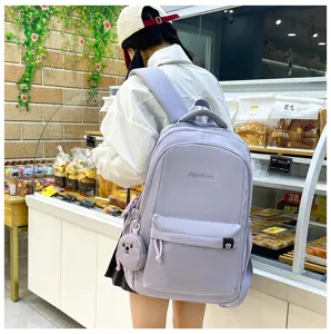 Dettaglio zaino in nylon color caramella, grande borsa scolastica per studenti con ciondolo.
