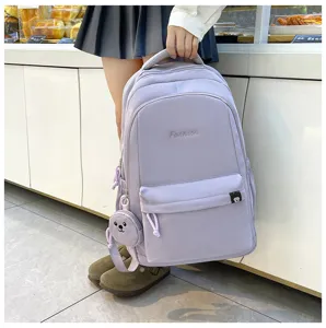 Dettaglio zaino studentesco in nylon lavanda con grazioso ciondolo orsetto e borsa spaziosa.