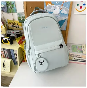 Dettagli dello zaino scolastico in nylon verde chiaro con ciondolo orsetto e grande spazio.