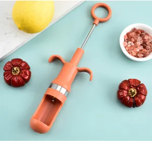 Vue détaillée de l'outil dénoyauteur manuel, plastique orange et inox, pour dattes.