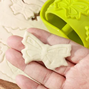 Green plastic pastry cutter wheel for baking cookies, butterfly shaped dough roller tool.