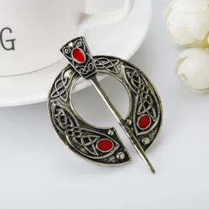 Detailed view of vintage Viking Celtic penannular brooch with red stone inlay and knotwork.