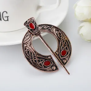 Vintage Viking brooch and Celtic knot shawl pin detail shot, retro bronze finish with red stones.