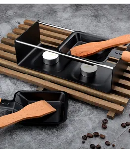 Mini ensemble à raclette à fromage avec spatules en bois et bougies chauffe-plat.