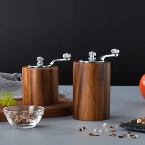 Manual walnut wood pepper and coffee grinder set with metal crank for kitchen use.