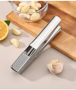 Detail view of stainless steel garlic press with garlic cloves and cutting board scene.