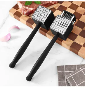 Stainless steel meat tenderizer detail view showing dual heads with spikes and blades on board.