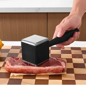 Detailed view of the stainless steel meat tenderizer mallet in action on a wooden board.