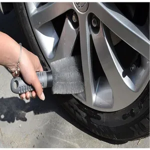 Vue détaillée d'une brosse de nettoyage pour jantes grises en action sur une roue.