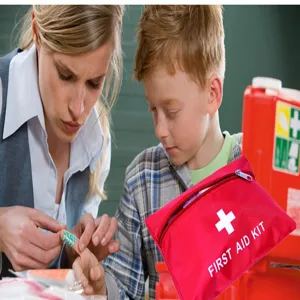 Detail view of a portable red first aid kit bag with clear white cross symbol for emergency medical use.