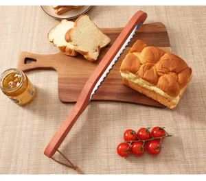 Detailed view of wooden bread knife with serrated blade on cutting board with toast and tomatoes.