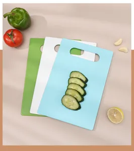 Detail view of plastic cutting boards in blue, white, and green with fresh cucumber slices.
