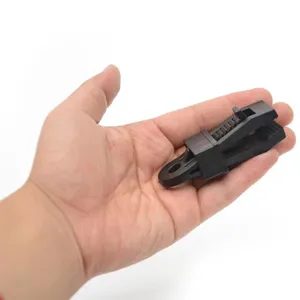 Close-up detail van zwarte plastic dekzeilclip met vergrendelingsmechanisme en ophanggat getoond.