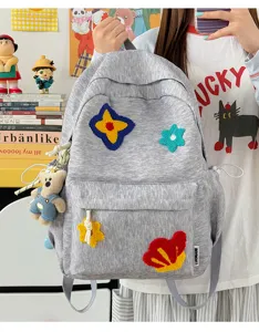 Gedetailleerd detailoverzicht van de grijze nylon schoolrugzak met leuke gekleurde patches.