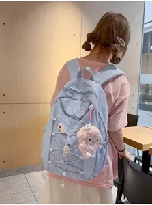 Detailansicht des blauen karierten Rucksacks mit Schleifenmuster und süßem Plüschanhänger.
