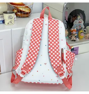 Detailansicht des niedlichen weißen Rucksacks mit roten Karo-Trägern und bunten Punkten.