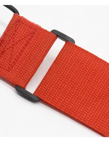 Detail shot of orange luggage strap and black plastic buckle, durable and adjustable.