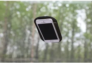 Detail view of black silicone car anti-slip pad holding smartphone securely on glass.