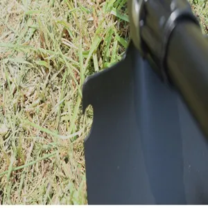 Gros plan détaillé d'une tête de pelle pliante de camping reposant sur herbe verte.
