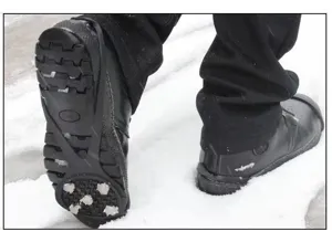 Detailansicht von Gummi-Eisspikes mit Metallstollen, die fest auf verschneitem Boden greifen.
