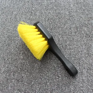 Detailed view of black plastic car cleaning brush with bright yellow bristles for wheel care.