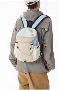 Detail view of a lightweight color-block backpack with bungee cord and clear printed lettering.