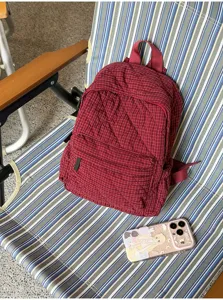 Detailed view of the dark red quilted plaid backpack showing texture and details.