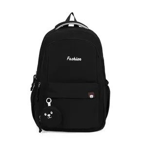 Dettaglio zaino scolastico in nylon nero con tasca frontale e simpatico ciondolo orsetto.