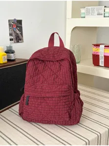 Red quilted grid backpack detail view showing soft fabric and front pocket design.