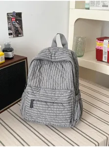 Close-up of a stylish grey quilted backpack with diamond stitching, featuring handy front pocket.