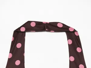 Close-up detail of brown and pink polka dot halter neck top strap, flat lay fashion.