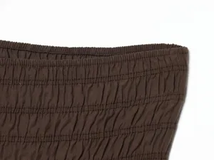 Primo piano del tessuto elastico arricciato marrone con trama plissettata fine e vestibilità elastica.