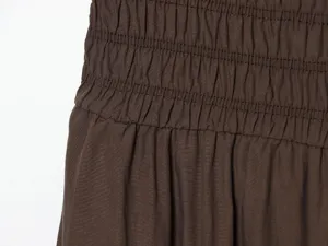 Dettaglio in tessuto marrone plissettato, texture della vita elastica arricciata primo piano.