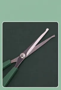 Pet grooming scissors detail view, stainless steel curved blade with comfortable green handle.