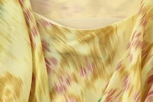 Close-up detail of women's printed dress fabric, soft texture, elegant drape and abstract pattern.