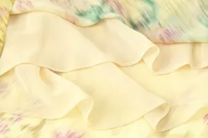 Detailed shot of layered printed dress fabric, soft texture, elegant ruffles design.