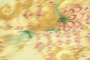 Close up detail view of women dress fabric with abstract floral yellow and pink print.