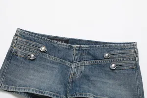 Détail de short en denim avec boutons décoratifs en métal, doubles coutures et étiquette.