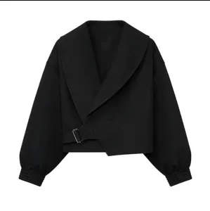 Black cropped jacket detail view, wide shawl lapel, side buckle belt, stylish ribbed cuffs.