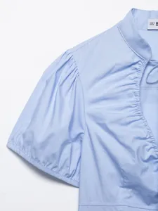 Primo piano dettagliato del top a maniche corte in popeline azzurro con arricciatura e nastro elegante.