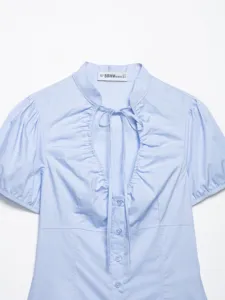Dettaglio top in popeline azzurro con elegante scollo annodato e maniche a palloncino.