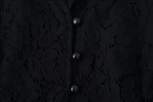 Close-up detail of elegant black lace fabric and buttons on women's top garment.