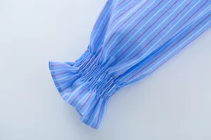 Nahaufnahme der blauen gestreiften Hemdmanschette mit gesmoktem Elastik und Rüschen.