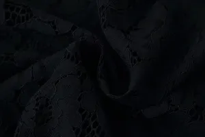 Close-up view of elegant black lace fabric, showing delicate floral pattern and fine texture.