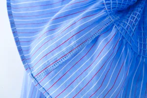 Nahaufnahme von blau gestreifter Damenbluse mit gesmoktem Kragen und feinen Nähten.