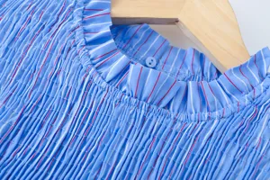 Nahaufnahme der blauen und weißen gestreiften Bluse mit Rüschenkragen und Plissee-Textur.