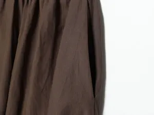 Vista dettagliata di pantaloni plissettati marroni da donna con tasca laterale e tessuto.