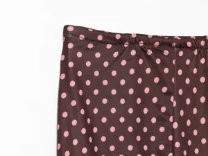 Brown and pink polka dot skirt elastic waistband detail close up, soft fabric design.