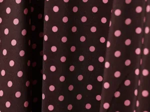 Detailed shot of elegant brown fabric with pink polka dots, showing fine texture and drape.